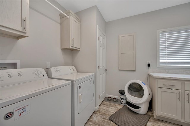 laundry area with cabinets, light wood-type flooring, and washer and clothes dryer