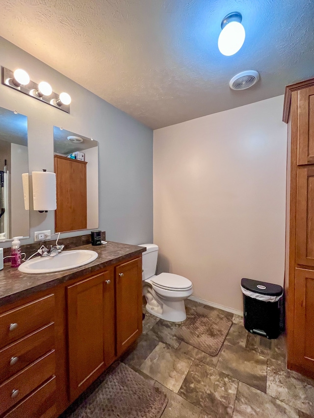 bathroom with vanity, toilet, and a textured ceiling