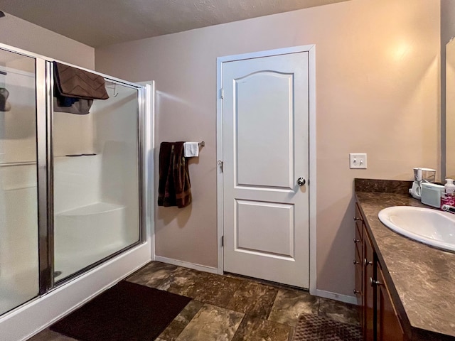 bathroom featuring a textured ceiling, walk in shower, and vanity