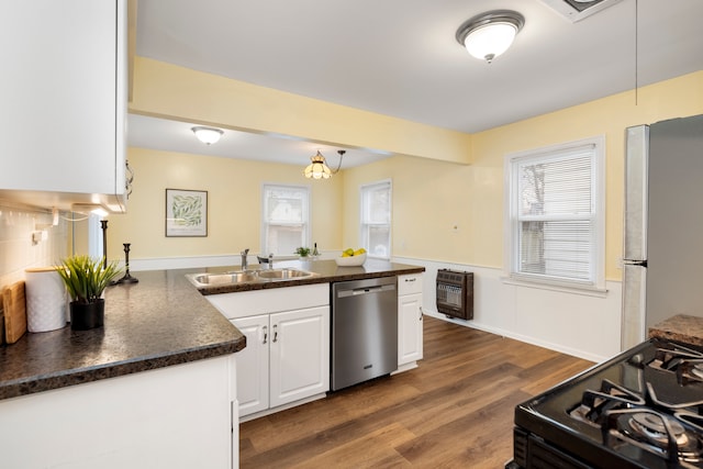 kitchen featuring sink, heating unit, appliances with stainless steel finishes, dark hardwood / wood-style flooring, and white cabinets