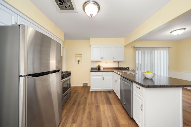 kitchen with stainless steel appliances, white cabinetry, sink, and dark wood-type flooring