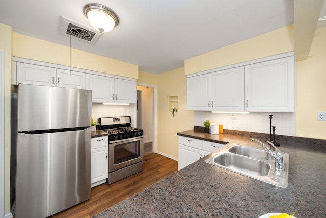 kitchen with sink, dark wood-type flooring, appliances with stainless steel finishes, white cabinetry, and decorative backsplash