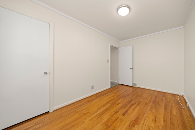 spare room featuring ornamental molding and light wood-type flooring