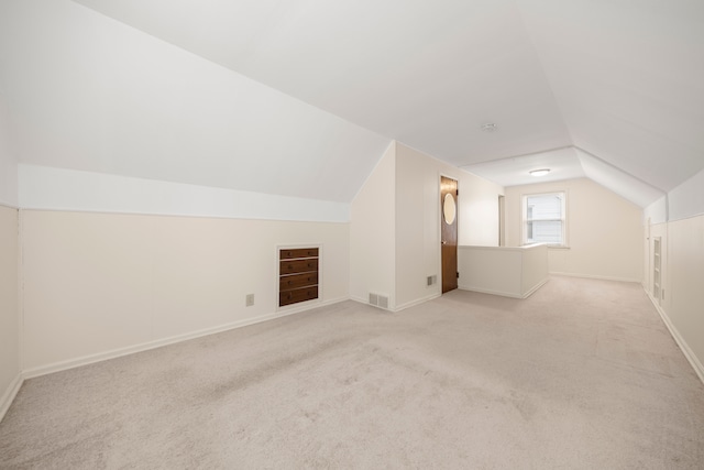 bonus room with vaulted ceiling and light carpet