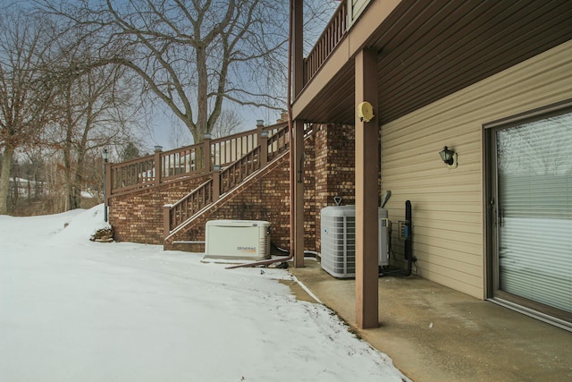 snow covered patio featuring central AC unit