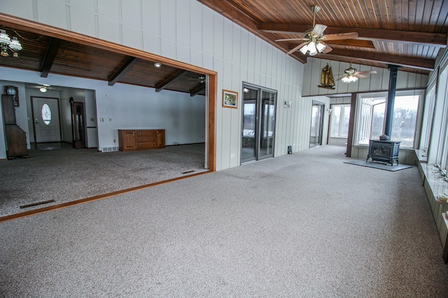 interior space with a wood stove, wooden ceiling, beam ceiling, and carpet floors