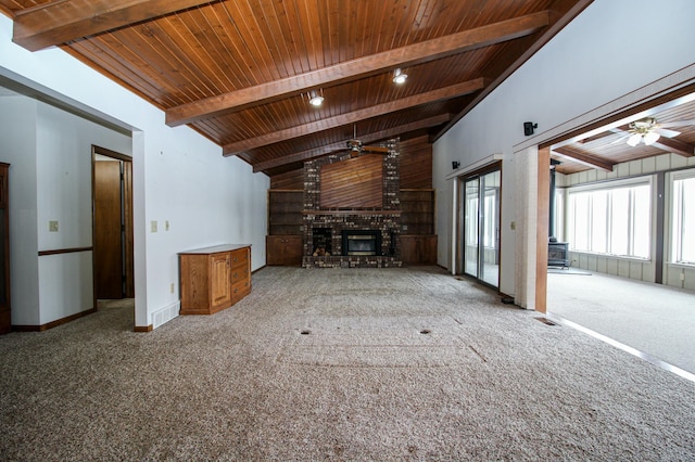 unfurnished living room featuring beamed ceiling, wooden ceiling, a fireplace, light carpet, and ceiling fan