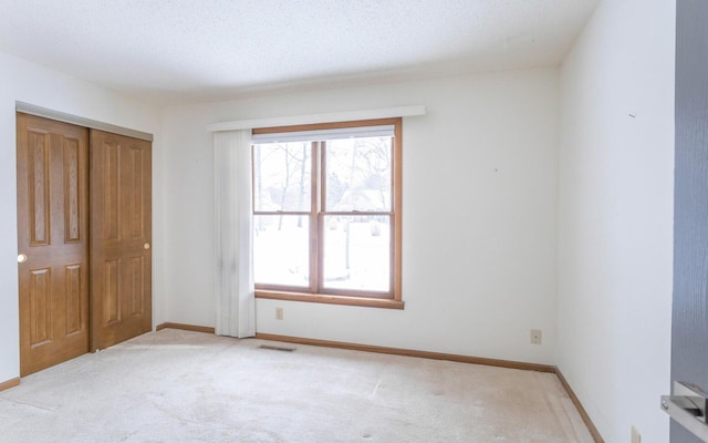 unfurnished bedroom with light carpet, a textured ceiling, and a closet