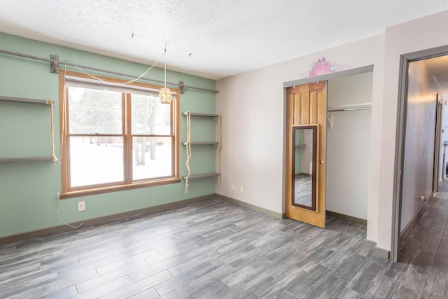 unfurnished bedroom with a textured ceiling, dark hardwood / wood-style floors, and a closet