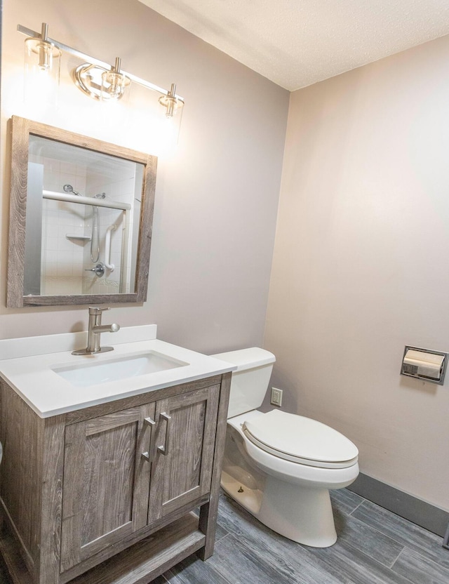 bathroom with a shower with shower door, a textured ceiling, toilet, and vanity