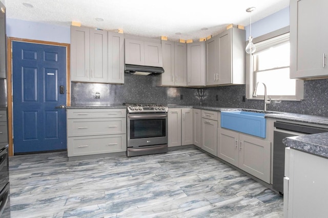 kitchen featuring stainless steel gas range, gray cabinetry, sink, decorative light fixtures, and dishwashing machine