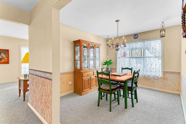 carpeted dining room featuring a wainscoted wall and a notable chandelier