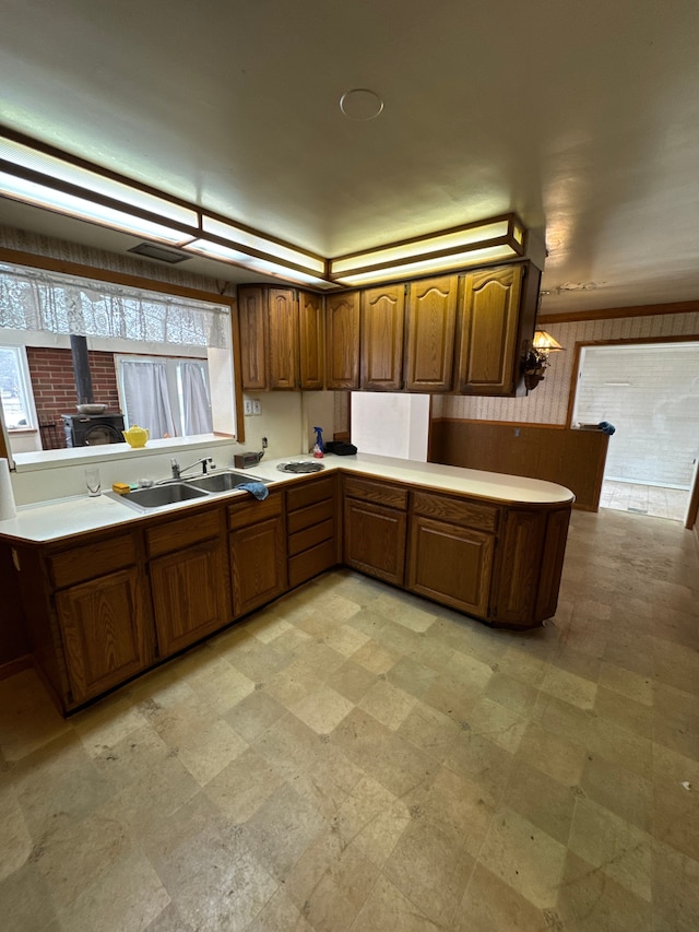 kitchen featuring kitchen peninsula, sink, and a wood stove