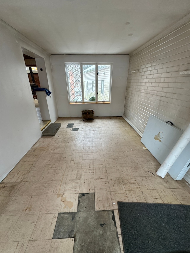 unfurnished room featuring brick wall