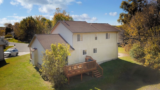 rear view of house featuring a wooden deck and a lawn