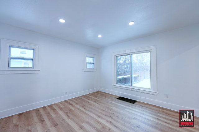 empty room with a wealth of natural light and light hardwood / wood-style floors