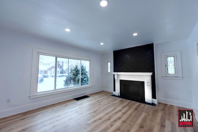 unfurnished living room with a fireplace and light hardwood / wood-style floors