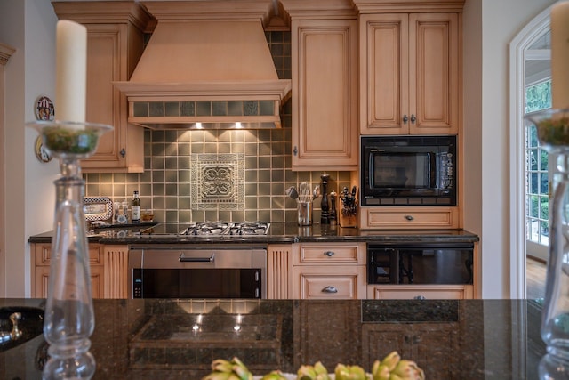 kitchen with premium range hood, dark stone countertops, decorative backsplash, and black appliances