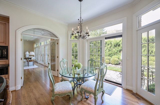 dining space with ornamental molding, a notable chandelier, and light hardwood / wood-style flooring