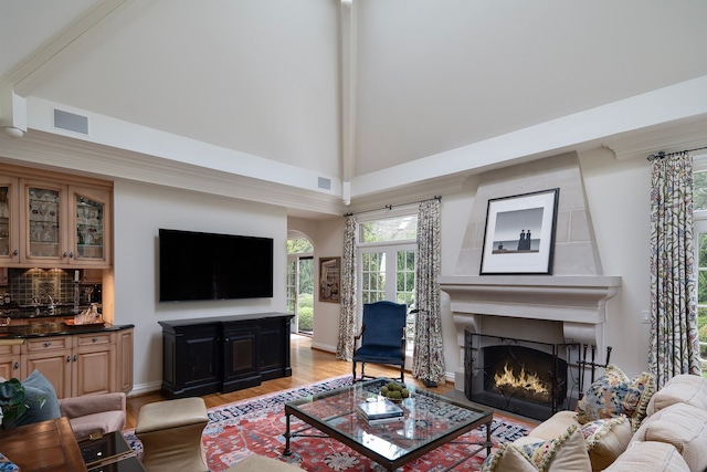 living room featuring high vaulted ceiling, a fireplace, and light hardwood / wood-style floors