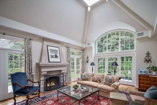 living room with hardwood / wood-style floors, high vaulted ceiling, a large fireplace, plenty of natural light, and french doors