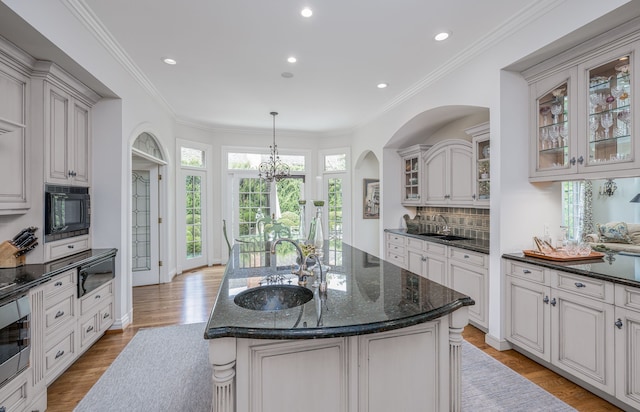 kitchen featuring sink, light hardwood / wood-style floors, a kitchen island with sink, and black microwave