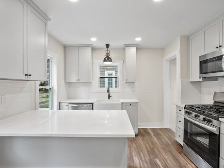 kitchen with sink, wood-type flooring, white cabinets, and appliances with stainless steel finishes