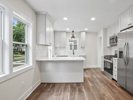 kitchen featuring stainless steel appliances, a healthy amount of sunlight, white cabinets, and kitchen peninsula