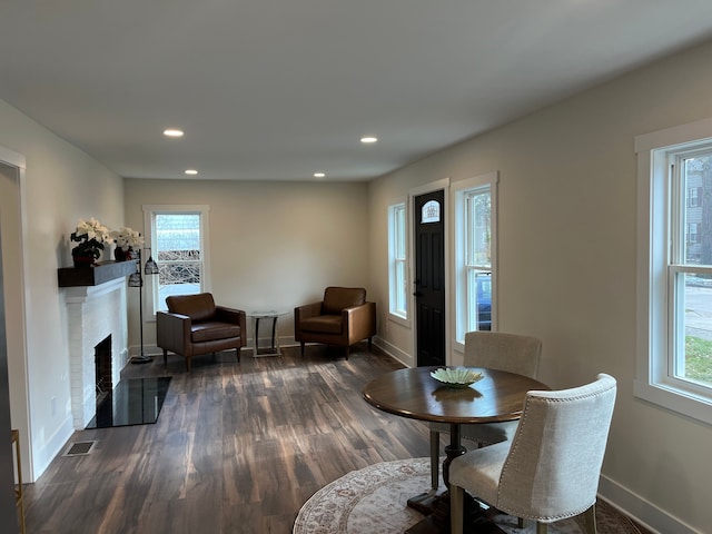 dining area with a healthy amount of sunlight, dark wood-type flooring, and a fireplace