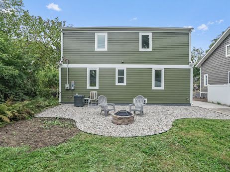 rear view of property with a fire pit, a lawn, and a patio