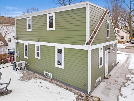 snow covered rear of property with ac unit