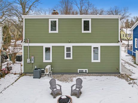 snow covered house featuring cooling unit and an outdoor fire pit