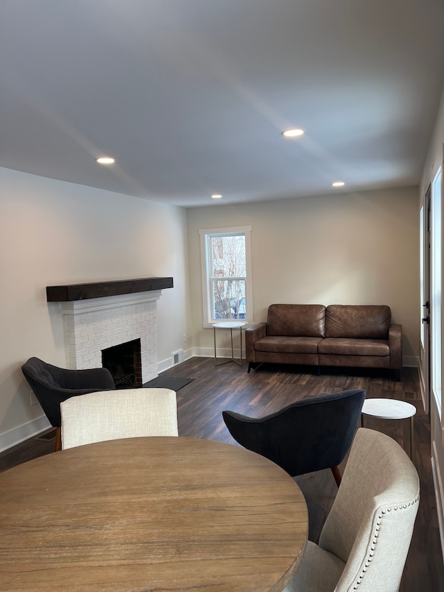 living room featuring dark hardwood / wood-style flooring and a brick fireplace