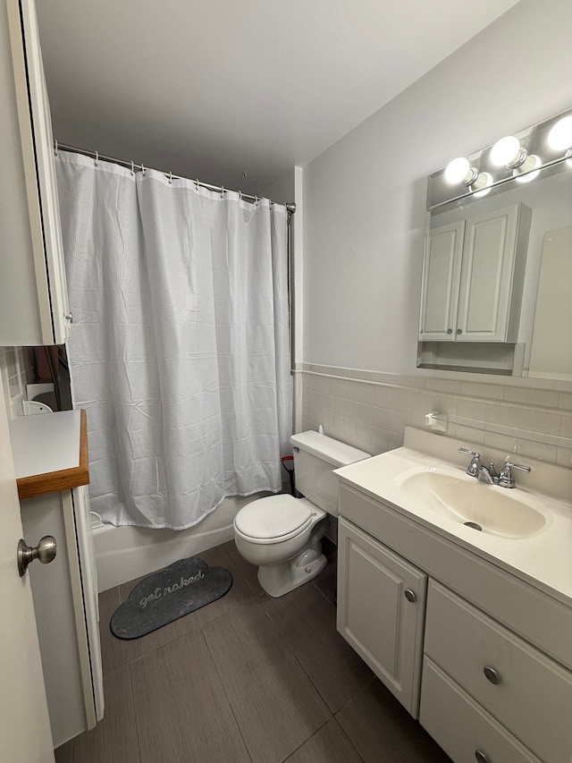 full bathroom with tile walls, shower / tub combo, vanity, and toilet