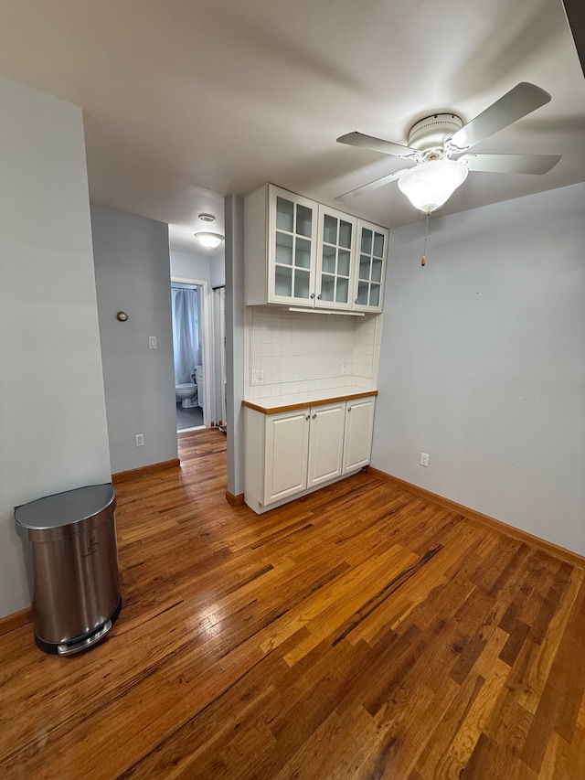 kitchen with white cabinetry, decorative backsplash, light hardwood / wood-style floors, and ceiling fan