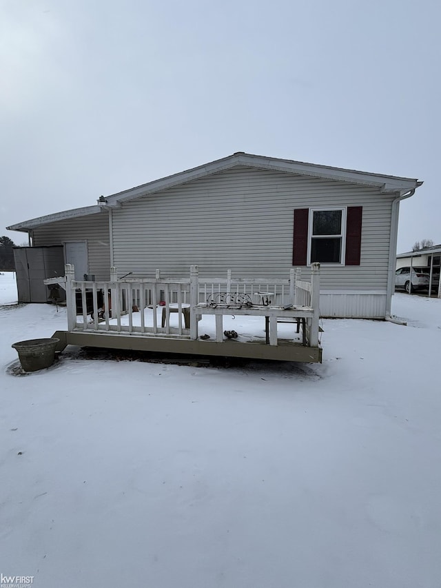 snow covered back of property with a deck