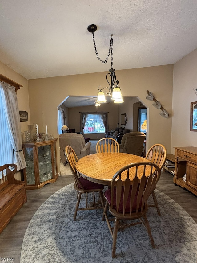 dining area featuring a textured ceiling, dark hardwood / wood-style flooring, and an inviting chandelier