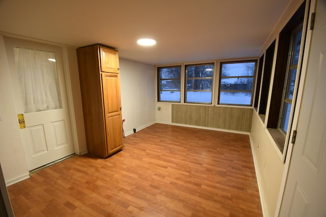 unfurnished bedroom with light hardwood / wood-style floors and wood walls