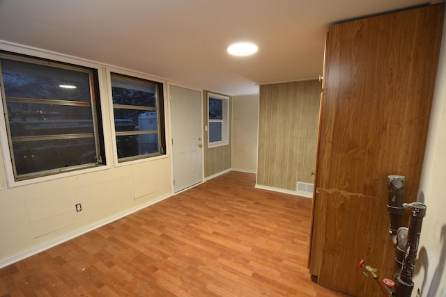 spare room with light wood-type flooring and wood walls