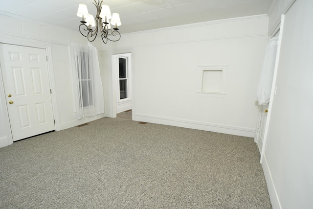 unfurnished room with ornamental molding, carpet floors, and an inviting chandelier