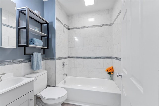 full bathroom with tile walls, toilet, vanity, and tiled shower / bath