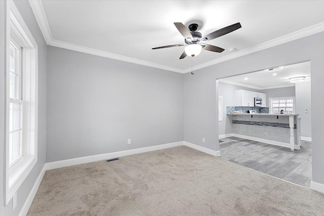 unfurnished room with ceiling fan, crown molding, and light carpet