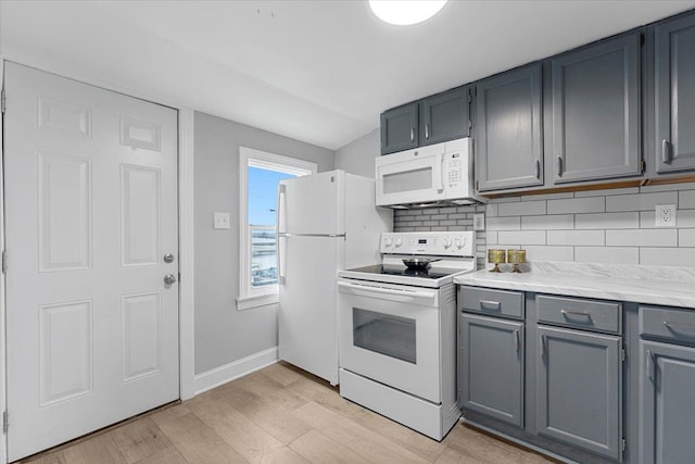 kitchen featuring light wood-type flooring, white appliances, decorative backsplash, and gray cabinets