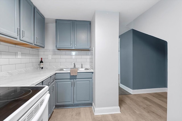 kitchen with decorative backsplash, sink, and light wood-type flooring