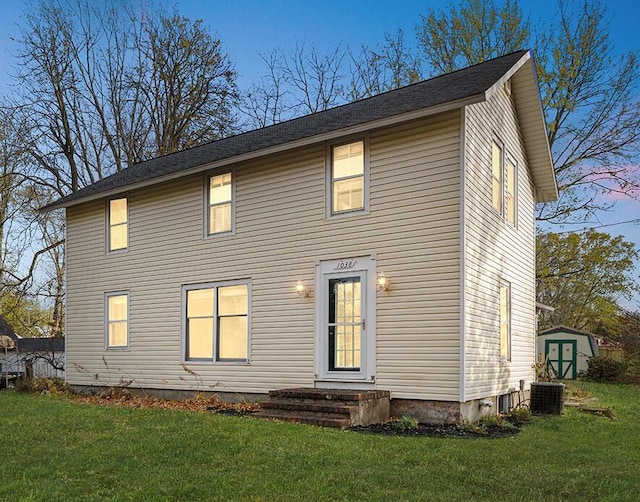 view of front of house featuring a lawn, central AC, and a shed