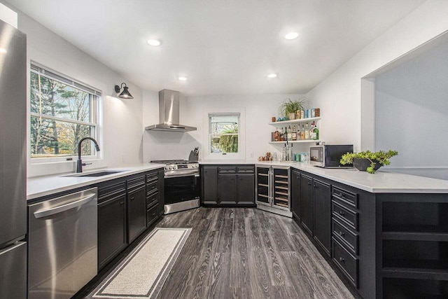 kitchen with sink, dark wood-type flooring, stainless steel appliances, wall chimney exhaust hood, and beverage cooler