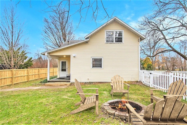 rear view of property with an outdoor fire pit and a lawn