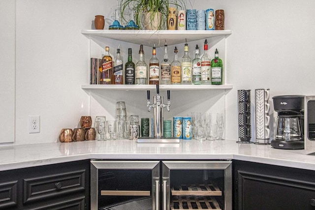 bar featuring beverage cooler and light stone counters