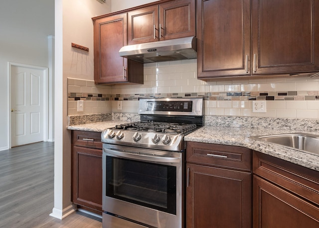 kitchen featuring light hardwood / wood-style floors, tasteful backsplash, gas range, and light stone countertops