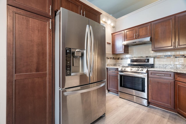 kitchen featuring light stone countertops, appliances with stainless steel finishes, light wood-type flooring, ornamental molding, and backsplash